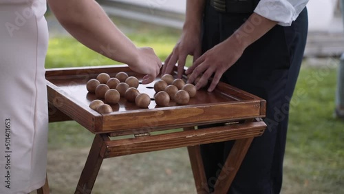 Man and woman are playing strategic wooden board game of nim at outdoor party. People remove balls from field. Intellectual game for development of ingenuity. Illuminates playing field on green lawn.
