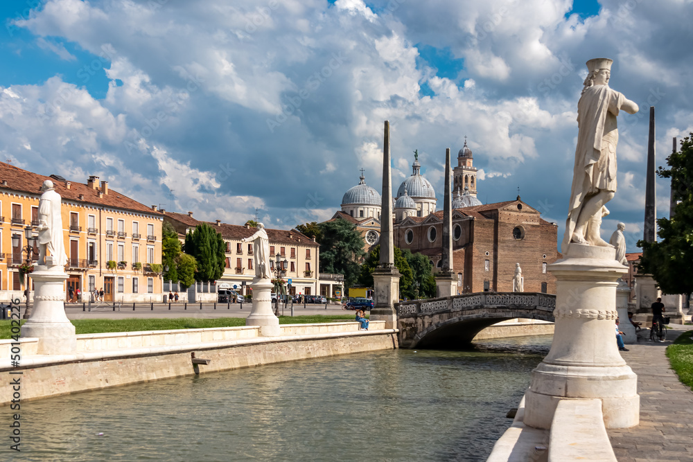 Scenic view on Prato della Valle, square in the city of Padua, Veneto, Italy, Europe. Green island at center, Isola Memmia surrounded by canal bordered by two rings of statues. Basilica of St Giustina