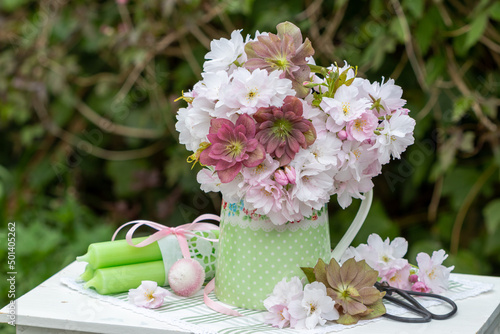 Blumenstrauß mit Lenzrosen und Zierapfel-Blüten in Vase im Garten photo