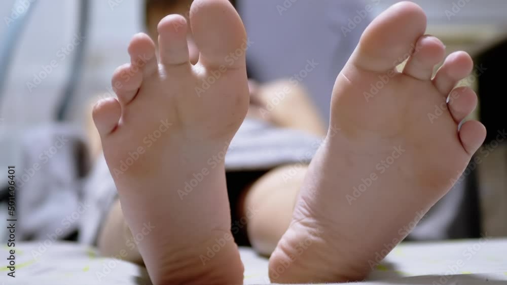 Video Stock Closeup of Two Large Legs of a Sleeping Child on a Bed in
