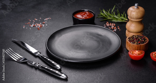 Empty round black plate on dark moody black background with copy space photo