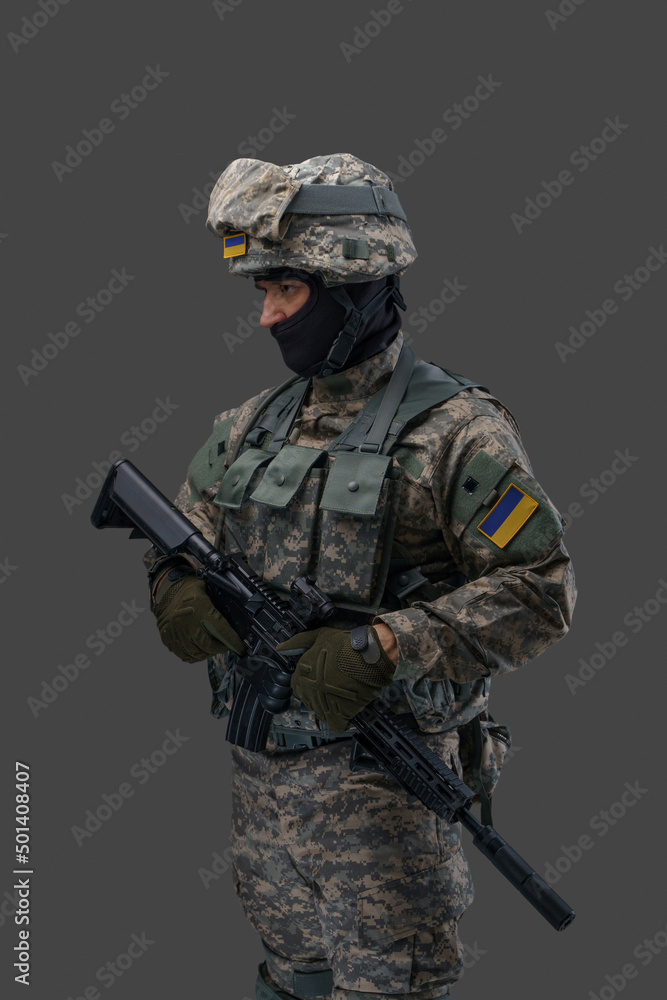 Portrait of soldier from ukraine with rifle dressed in uniform looking away isolated on gray background. Portrait of soldier from ukraine with rifle dressed in uniform looking away isolated on gray background.