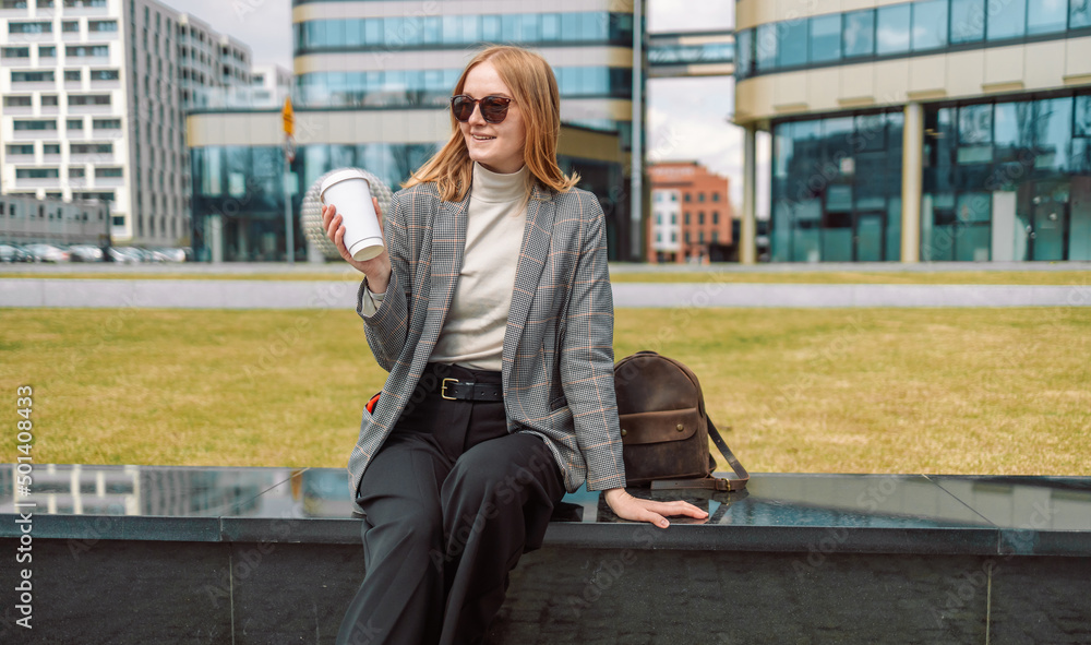 Fototapeta premium Woman holds a eco paper cup with coffee or tea and walks in spring park. Drink coffee time. Disposable paper cup. Take away. Hot beverage. Blank space. 