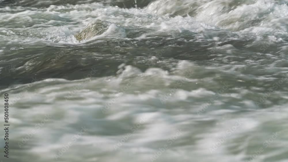 Rapid water flowing in spring river over small rock, closeup detail Rapid water flowing in spring river over small rock, closeup detail