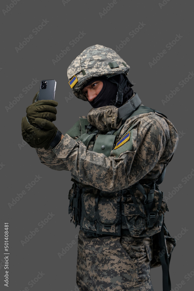 Shot of cheerful military man dressed in modern camouflage uniform taking selfie. Information warfare. Shot of cheerful military man dressed in modern camouflage uniform taking selfie. Information warfare.