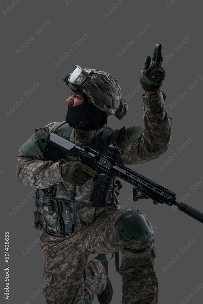Portrait of attacking soldier equiped with modern uniform and weapon against gray background. Portrait of attacking soldier equiped with modern uniform and weapon against gray background.