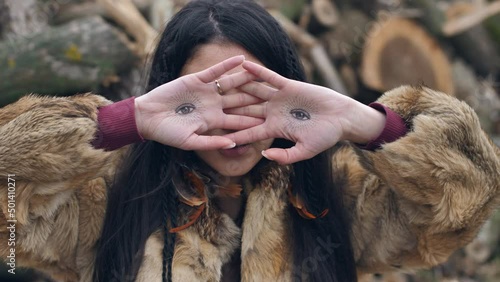 asian young woman covers her face with her hands with painted eyes on her palms.portrait of asian young mestizo woman