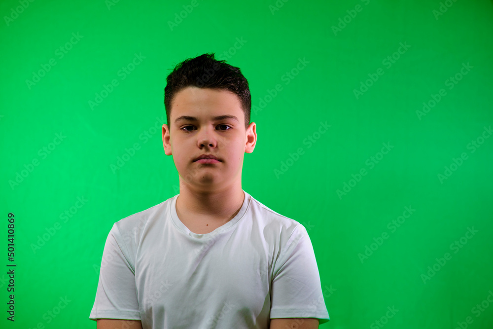 a boy on a green background looks at the camera. a boy on a green background looks at the camera.