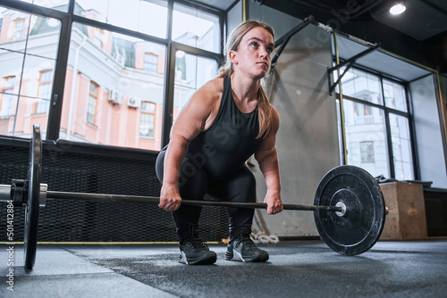 Muscular midget woman is squatting with barbell
