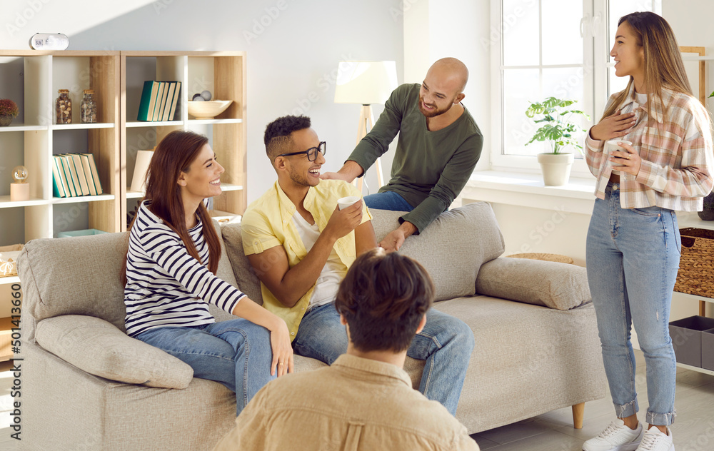 Diverse group of happy young friends having fun at cozy party at home. Cheerful mixed race multi ethnic people talking, drinking coffee, telling funny stories, laughing and enjoying good time together Diverse group of happy young friends having fun at cozy party at home. Cheerful mixed race multi ethnic people talking, drinking coffee, telling funny stories, laughing and enjoying good time together