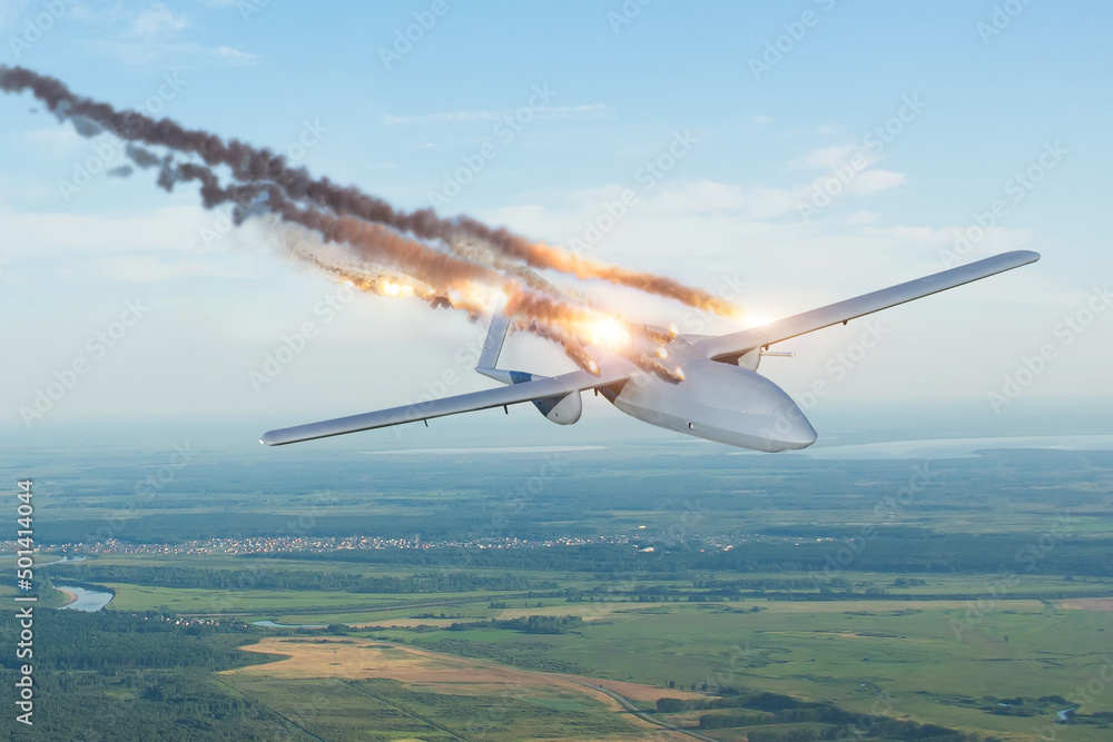 Fototapeta premium Blown-up strike unmanned military drone shot down by an enemy missile in the sky over a territory with settlements.