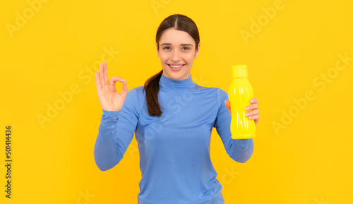 happy young lady hold sport bottle with water with ok gesture, hydration