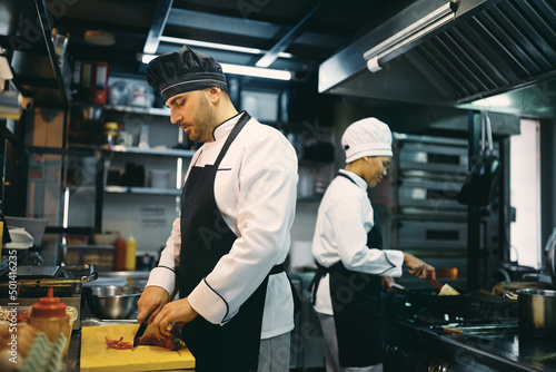 Two professional chefs preparing meal at restaurant kitchen.