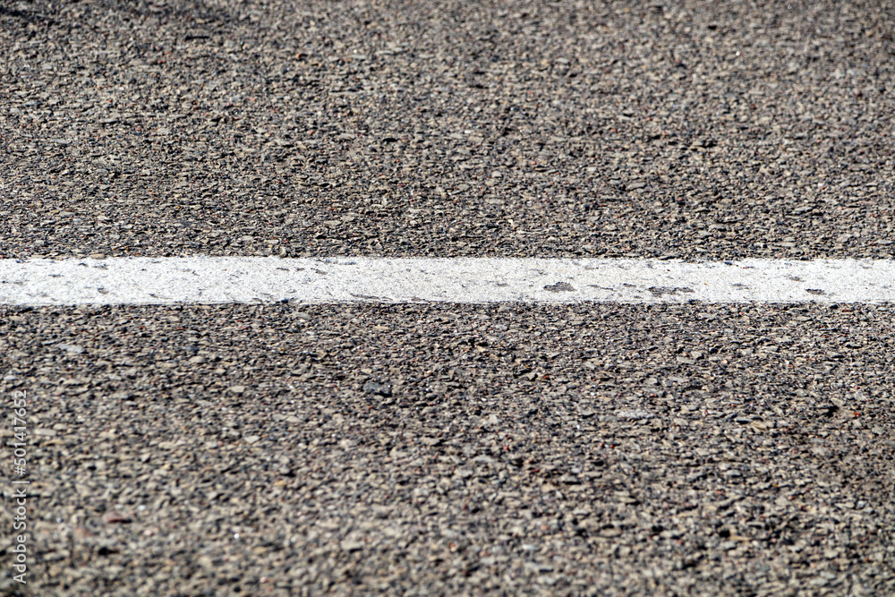 Fototapeta premium Asphalt background with white road marking line close-up