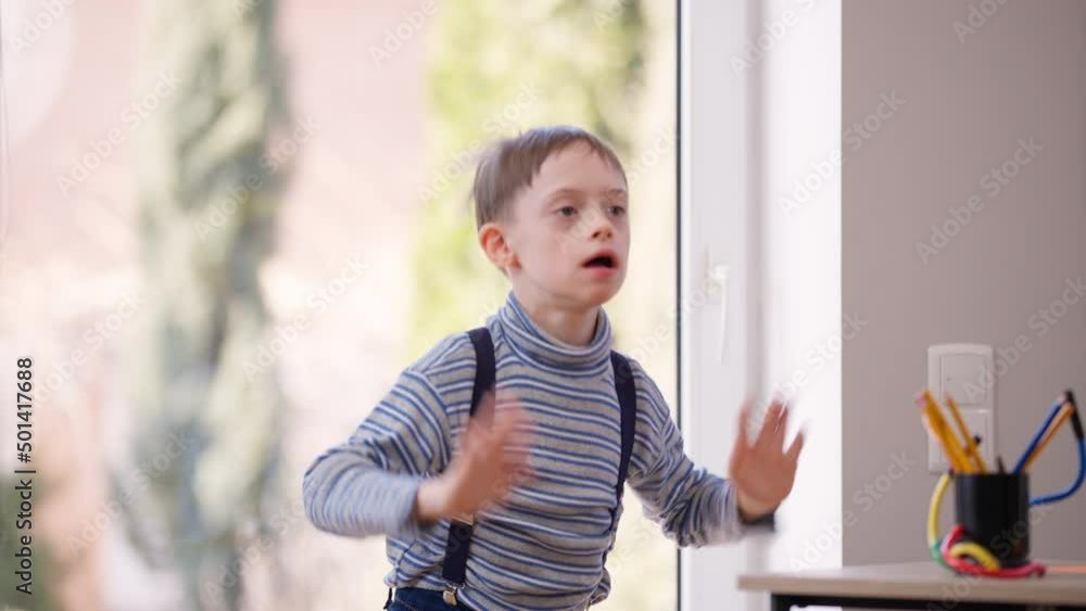 Hyperactive autistic boy jumping gesturing indoors laughing having fun. Portrait of cheerful happy Caucasian child with mental disorder enjoying leisure smiling. Autism and childhood concept Hyperactive autistic boy jumping gesturing indoors laughing having fun. Portrait of cheerful happy Caucasian child with mental disorder enjoying leisure smiling. Autism and childhood concept