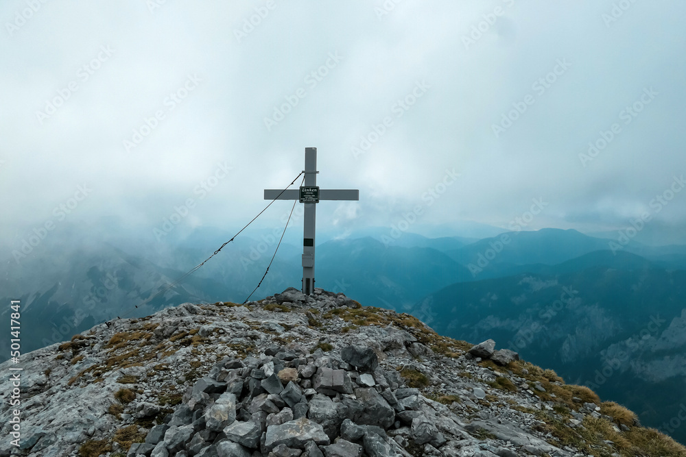 Scenic view from the summit cross of mount Zinken in the Hochschwab Region, Upper Styria, Austria. Valley is covered with clouds. Weather change on rainy spring day in the Alps, Europe. Alpine terrain