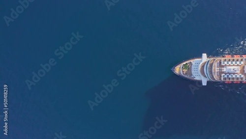 Aerial: large luxury cruise ship at sea. Big passenger ocean liner with pool on deck sailing in deep blue water top down view. Maritime travel across ocean tourism vacation holidays concept.
