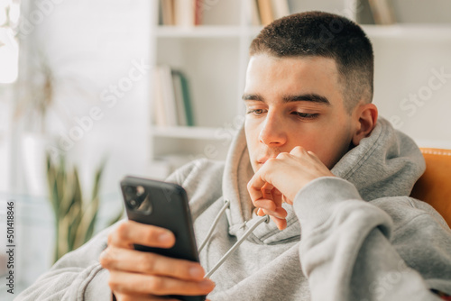 Fotografija young teenager at home looking at mobile phone