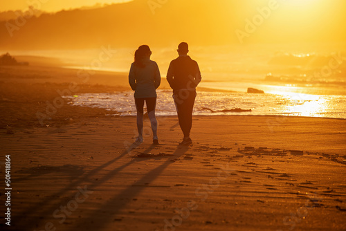 Fotografie couple strolling along the beach at sunset