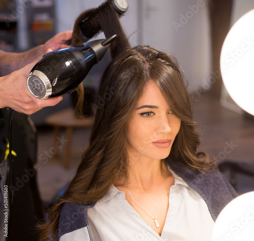 Young woman getting new hairstyle from hairdresser in the modern hair salon
