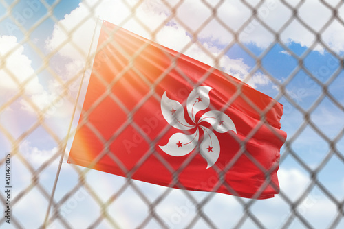 A steel mesh against the background of a blue sky and a flagpole with the flag of hong kong