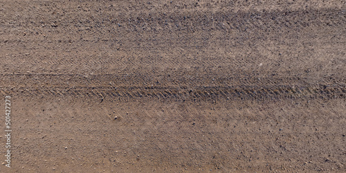 panorama of surface from above of gravel road with car tire tracks