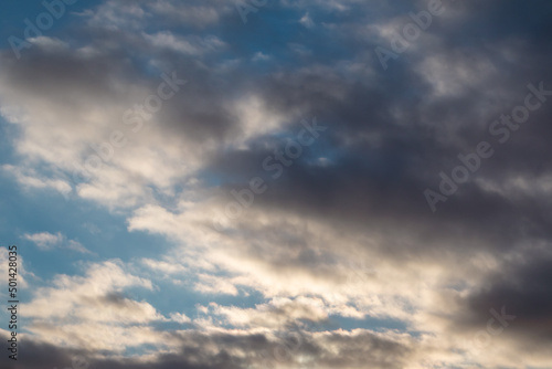 Dark stormy high clouds on blue sky with sunset shine, cloudscape background. Skyscape natural heavenly scenery