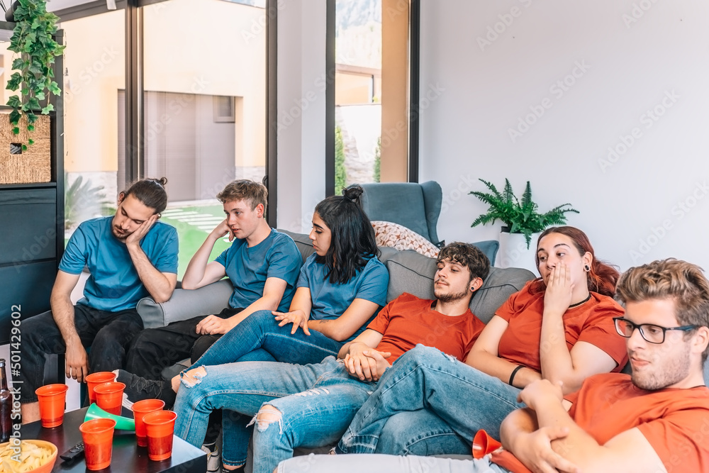 Football fans saddened by their team's defeat. Friends watching football in living room