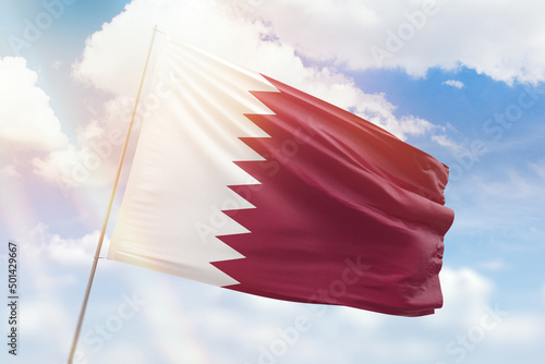 Sunny blue sky and a flagpole with the flag of qatar