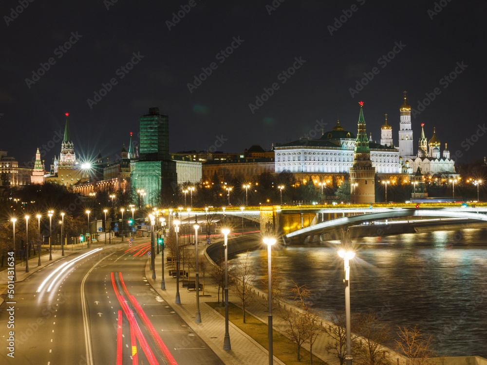 Moscow, Russia, Apr 13, 2022: Night view of Prechistenskaya embankment and the Moscow Kremlin from Patriarshy bridge. Car traces.