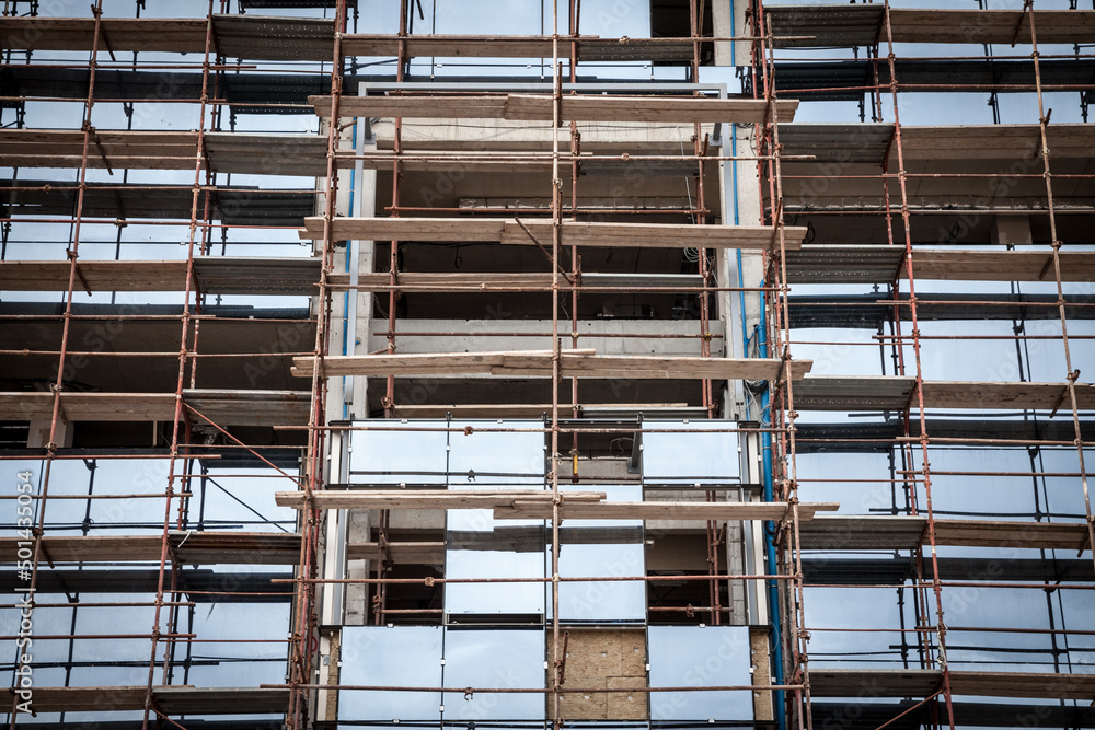 Naklejka premium Detail of a Scaffolding on a business skyscraper construction site in Belgrade, Serbia, on a sunny afternoon, with concrete structures ready for use to build an office space...