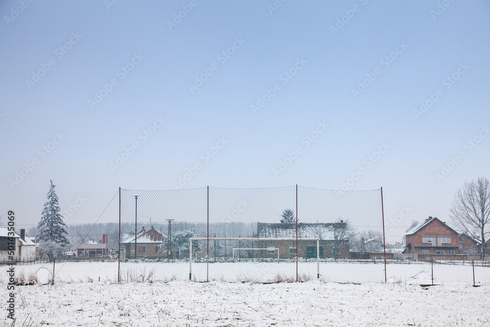 Selective blur on neglected and abandoned Soccer goals with football nets on display on a playground used as a soccer field in Bavaniste, Serbia, covered with snow during a cold winter afternoon....