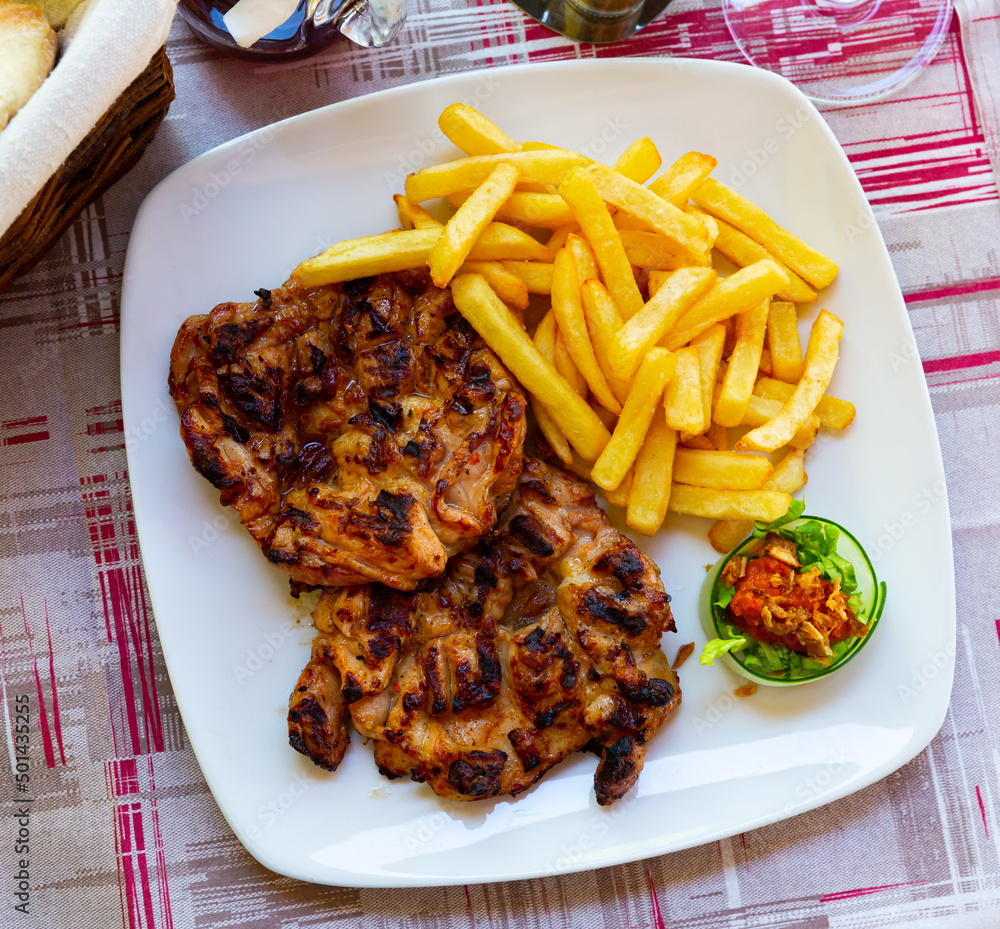 Traditional Balkan dish Pileci Batak - fillets of chicken thighs grill with garnish of fried potatoes
