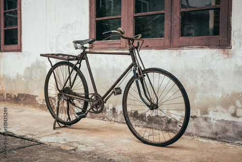 Old bike against the wall at home, old bicycle in vintage style.