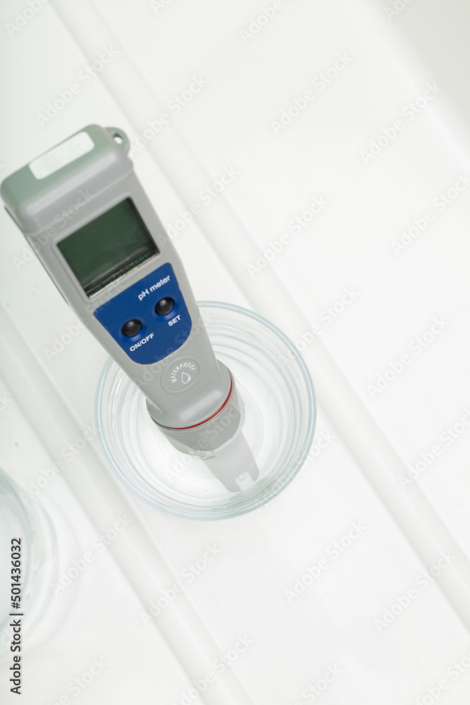 pH meter in a glass of water, and bottle on a white background. Measurement of the characteristics of drinking water. The hardness of the water. Drinking water quality analyzer. pH meter in a glass of water, and bottle on a white background. Measurement of the characteristics of drinking water. The hardness of the water. Drinking water quality analyzer.