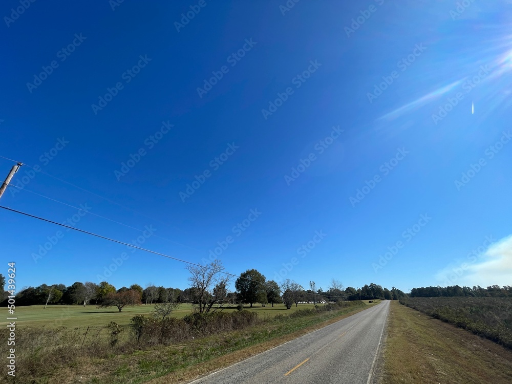A rural empty long road in the country and clear blue sky
