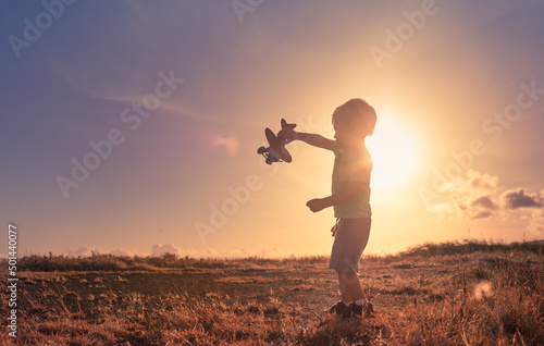 Canvas Little child playing with airplane at sunset