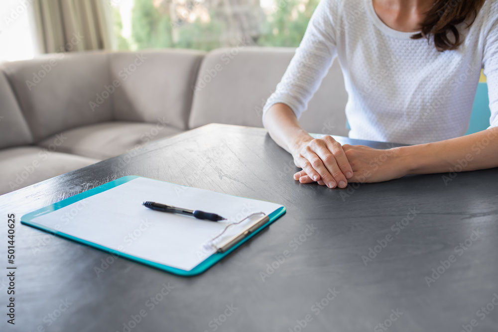 Woman sitting at table with blank paper waiting for interview Woman sitting at table with blank paper waiting for interview