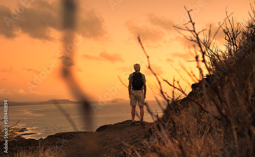 Thoughtful man hiker standing on a hill facing the sunset 
