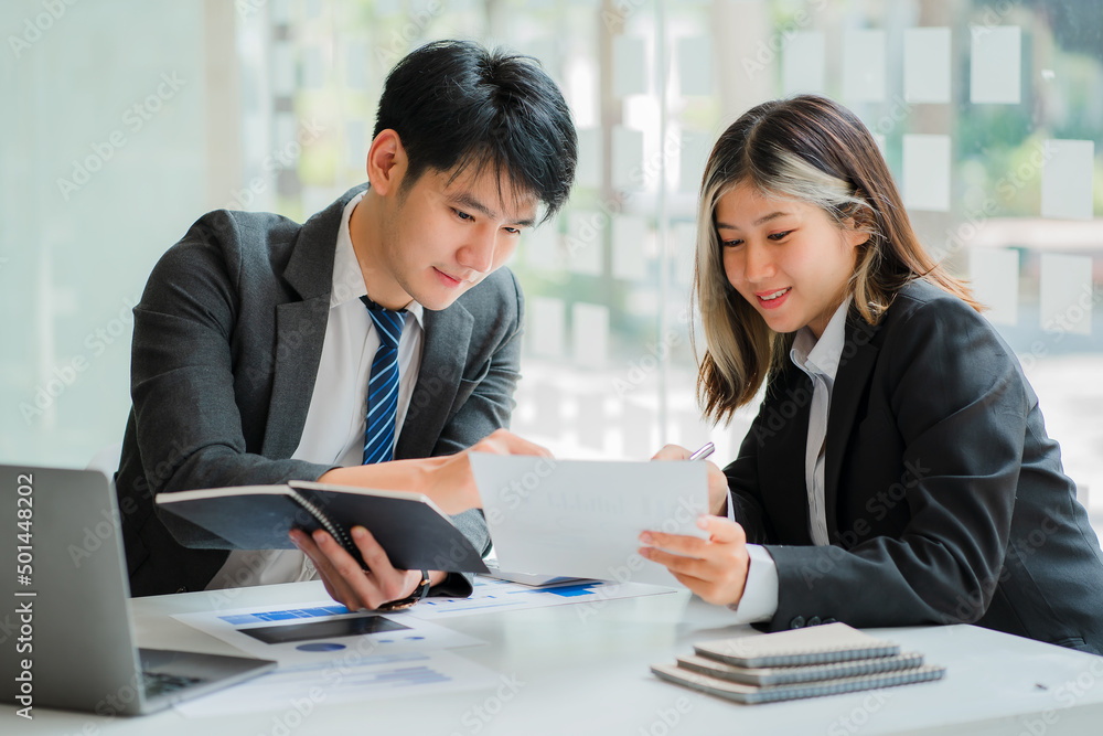 Two young Asian businessmen discuss business in a conference room brainstorming ideas for a successful modern office startup. Two young Asian businessmen discuss business in a conference room brainstorming ideas for a successful modern office startup.