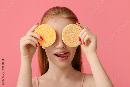 Funny woman with makeup sponges on color background photo