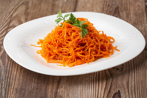 Delicious and spicy carrot spaghetti. Delicious spicy juicy bright Korean carrots on a wooden background. Asian cuisine