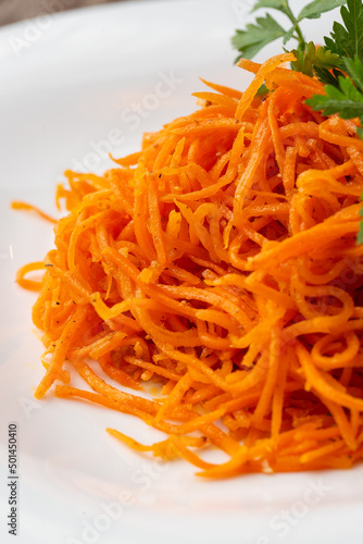 Delicious and spicy carrot spaghetti. Delicious spicy juicy bright Korean carrots on a wooden background. Asian cuisine