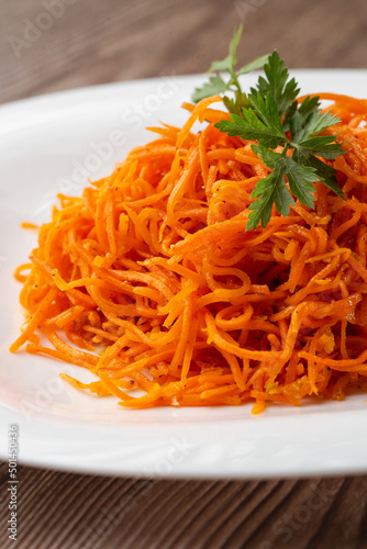 Delicious and spicy carrot spaghetti. Delicious spicy juicy bright Korean carrots on a wooden background. Asian cuisine