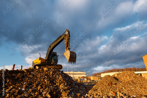 Building excavator with bucket stands on concrete waste