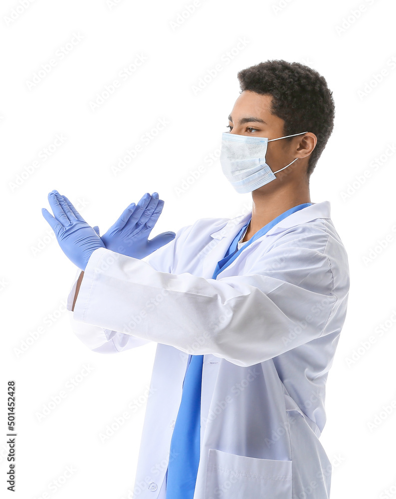 Young African-American doctor in medical mask showing stop gesture on white background. Immunity concept Young African-American doctor in medical mask showing stop gesture on white background. Immunity concept