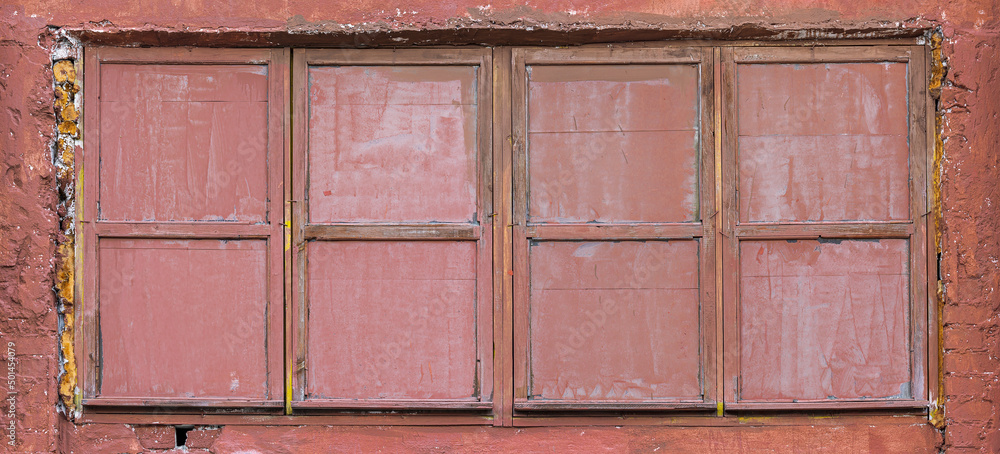 wood window with painted glass on red plaster wall. abandoned industrial building background.