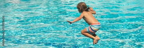 Child jumping in swimming pool. Kid having fun on summer vacation. Banner for header, copy space. Poster for web design.