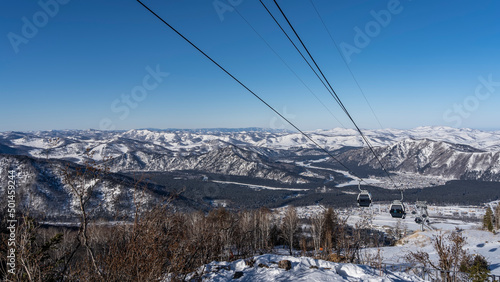 Fotografering A cable car over a snowy valley