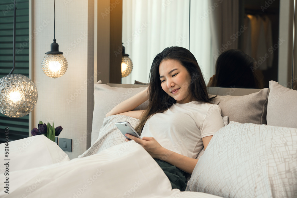 Asian woman in bed checking social apps with smartphone in morning. Asian woman in bed checking social apps with smartphone in morning.